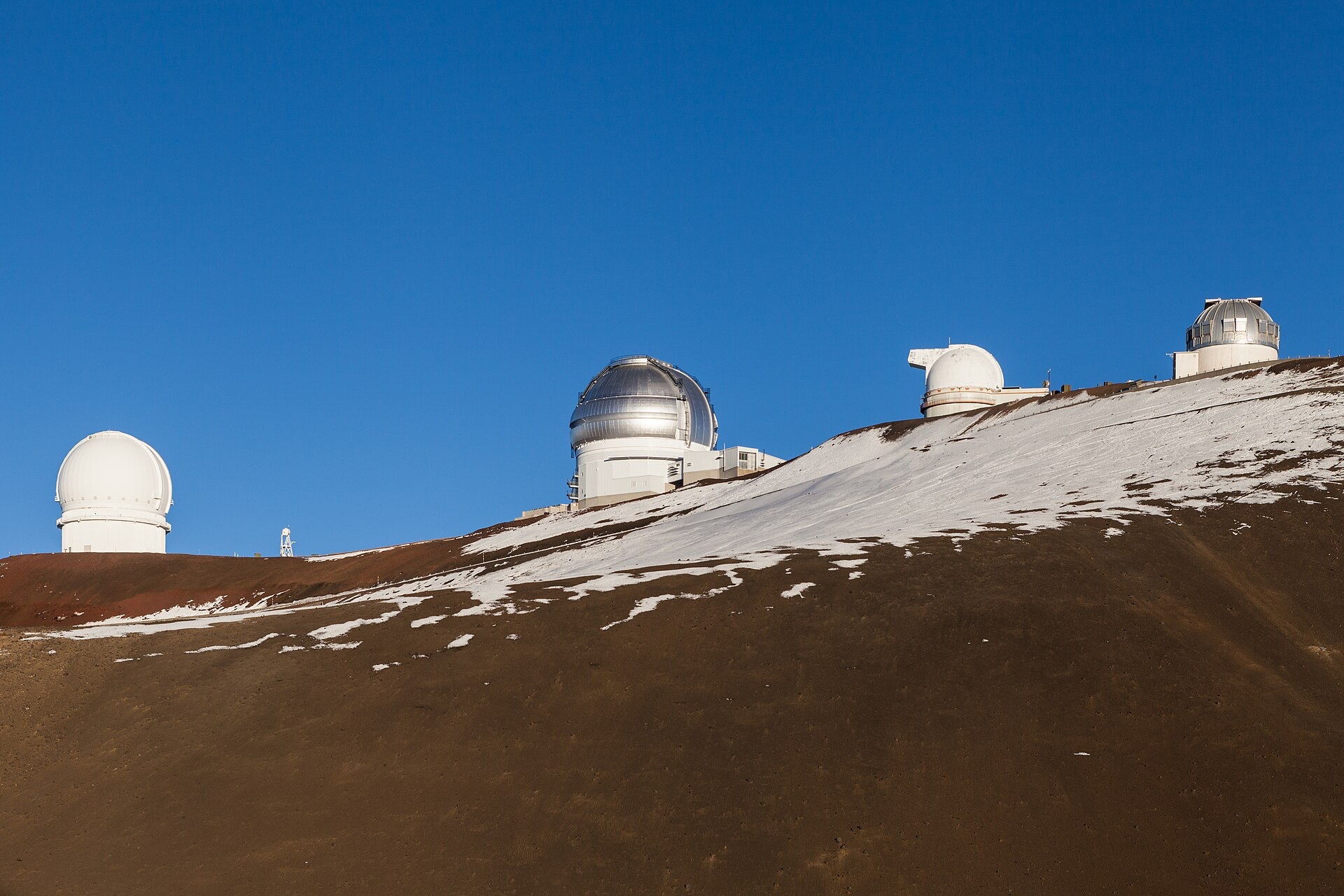Observatory domes on the summit of Mauna Kea with snow on the cinder slopes